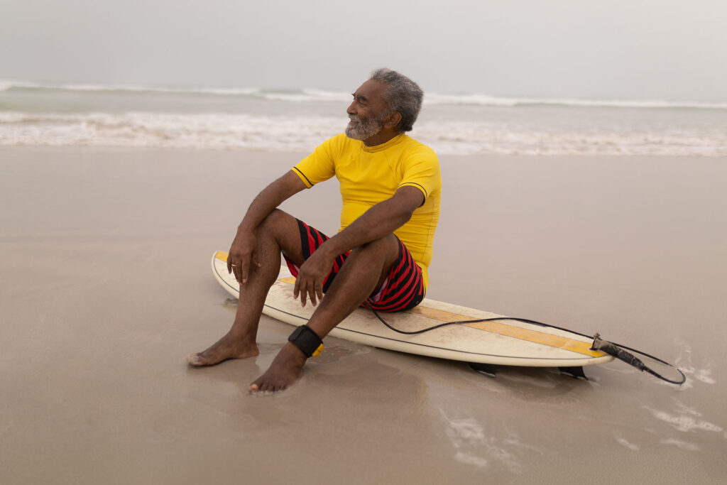 Advita Ortho Patient Education Man sitting on surf board at beach